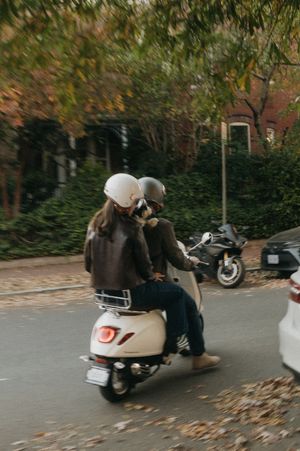 Sequence of a white scooter being parked on a street with autumn leaves during daytime.