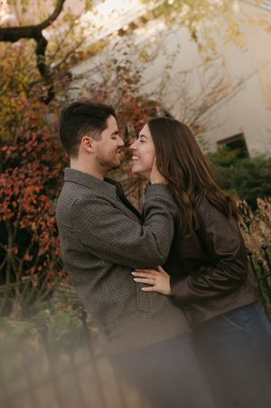Couple sharing intimate moment outdoors with autumn foliage in background during golden hour.