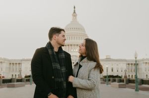 A couple shares a romantic moment in front of the US Capitol Building during an autumn day.