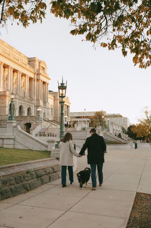 People walking along a wide pathway leading to the US Capitol building during sunset.