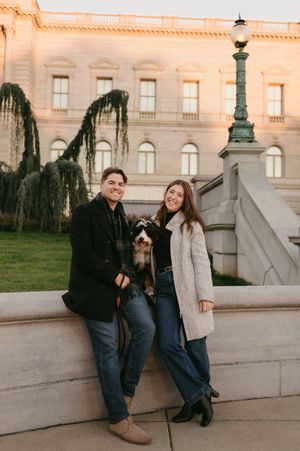 Couple posing together on stone steps at sunset with warm glowing architecture in background.