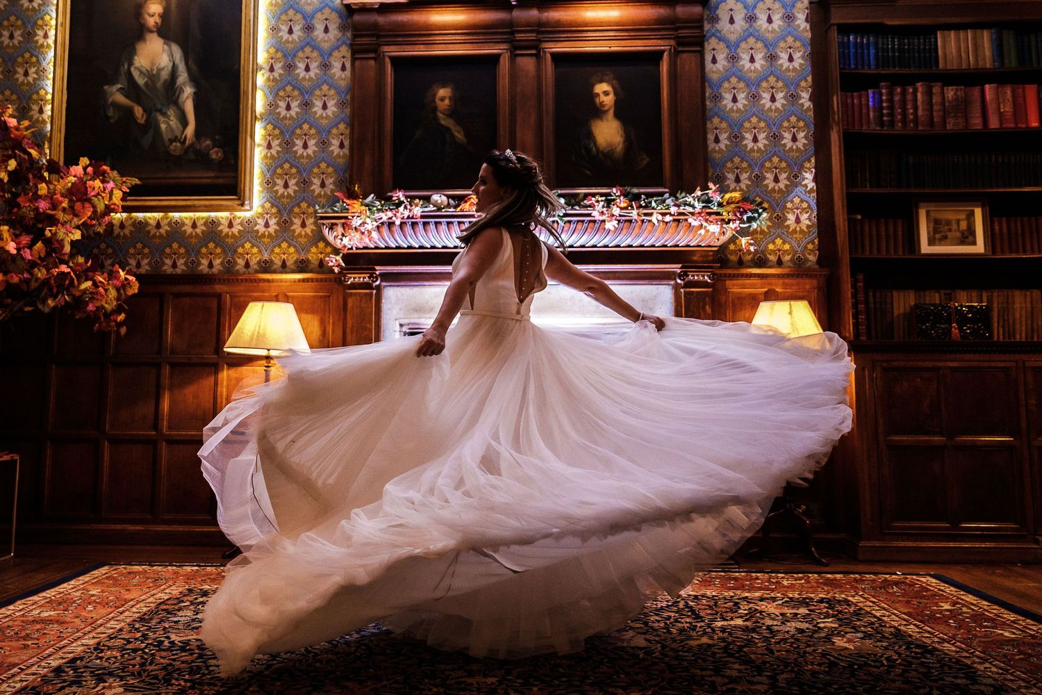Bride dancing night portrait in the Hodsock Priory Panelled Hall with lights glowing in the background