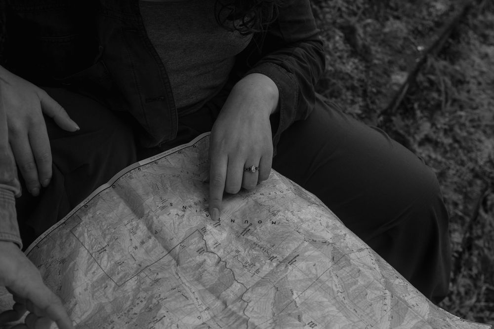 Two hands delicately touch and intertwine against a dark background in an intimate gesture.