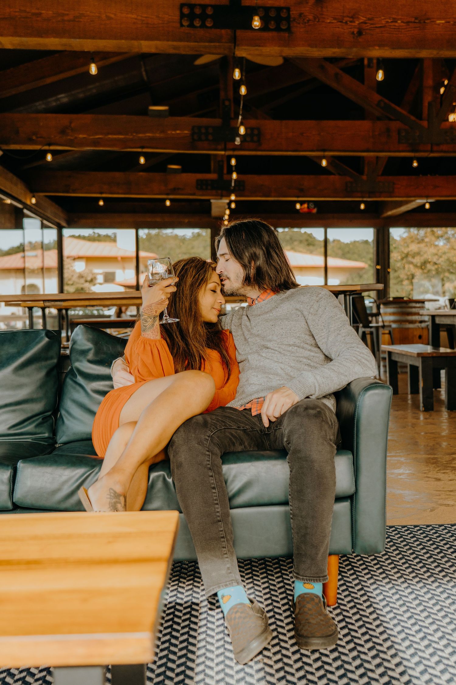 Couple lounging on grey couch with chevron pattern rug in rustic setting.
