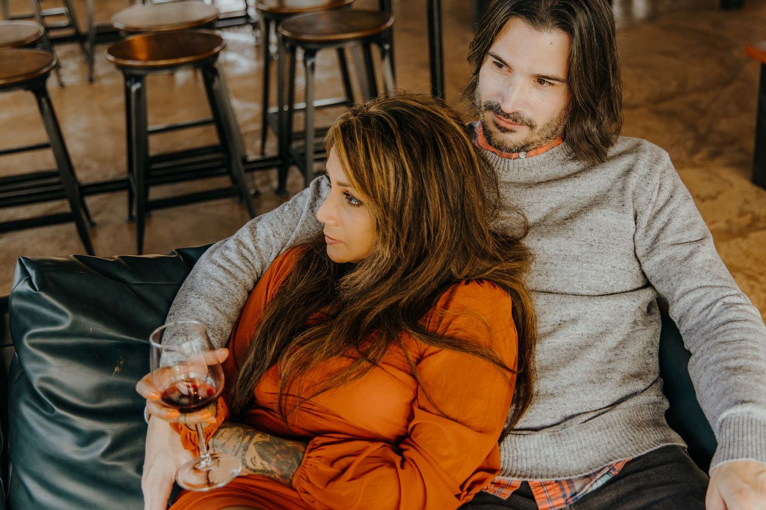 Two people sharing laughter while wine tasting in a rustic indoor space.
