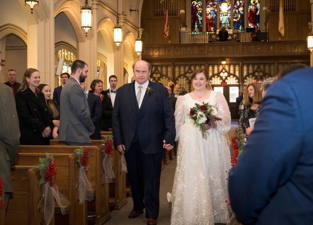 Wedding ceremony in a beautiful traditional church with stained glass windows and hanging pendant lights.