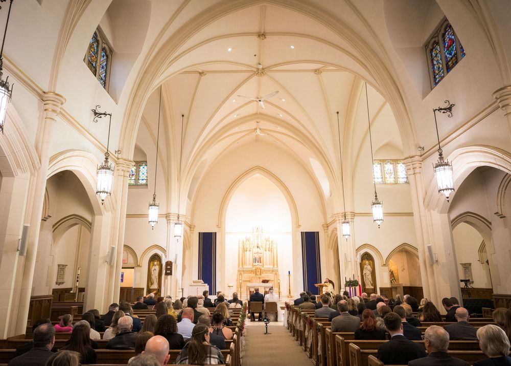 Interior of a beautiful church with vaulted ceilings and pews filled with wedding guests.