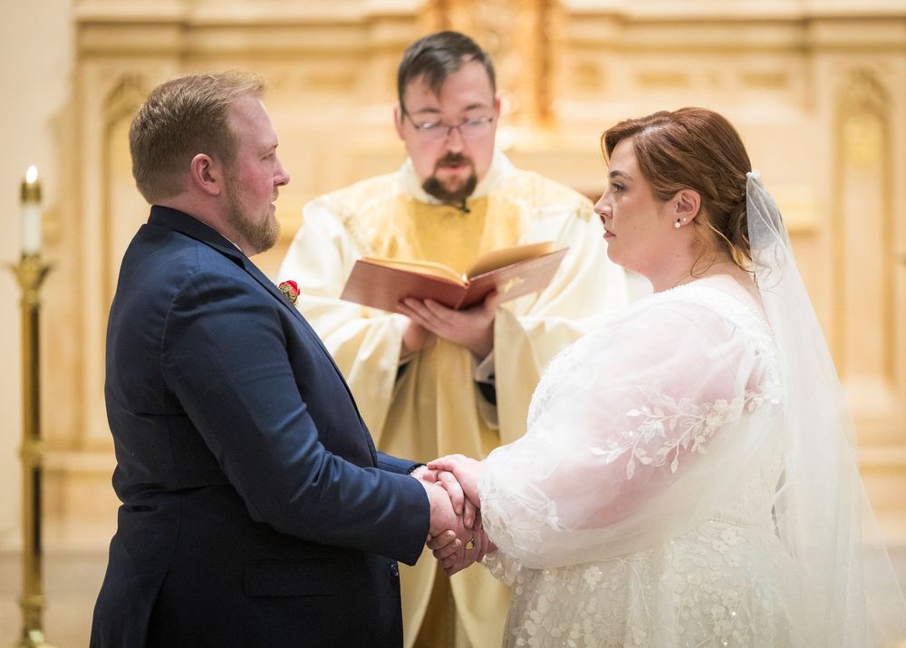 Couple shares a tender dance moment in an elegant ballroom with ornate gold decor.