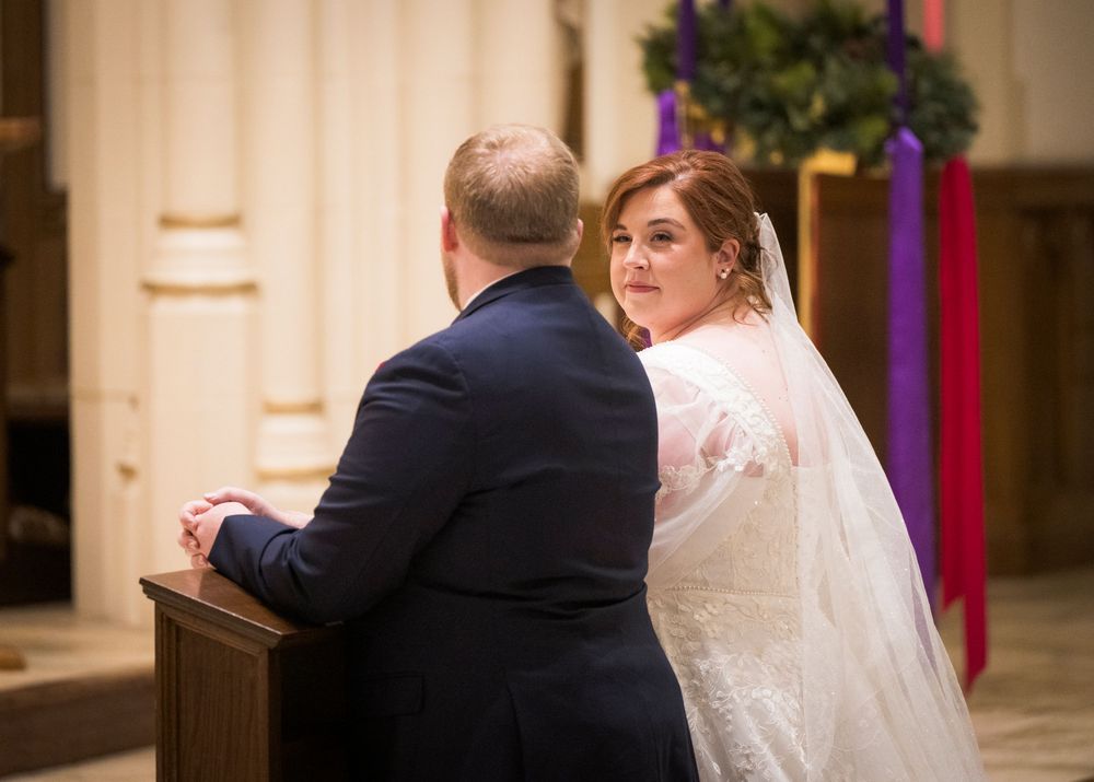 Wedding celebration in a church sanctuary with white drapes and red accents.
