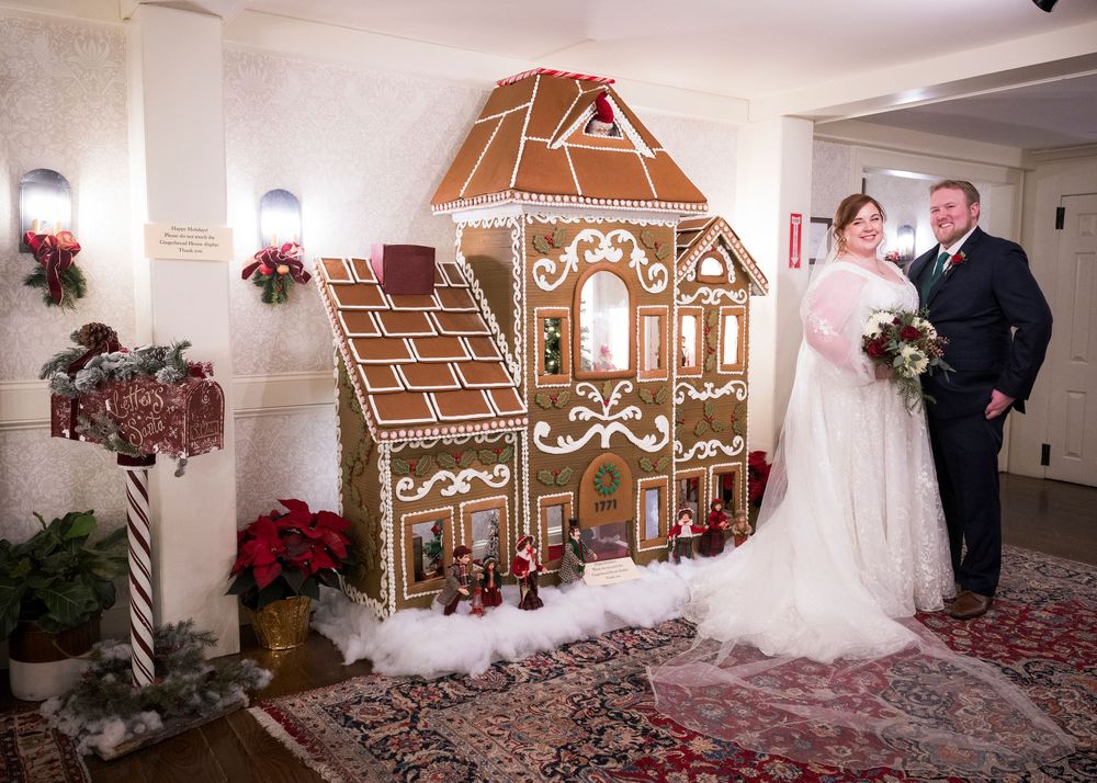 Large decorative gingerbread house display with holiday decorations and poinsettias.