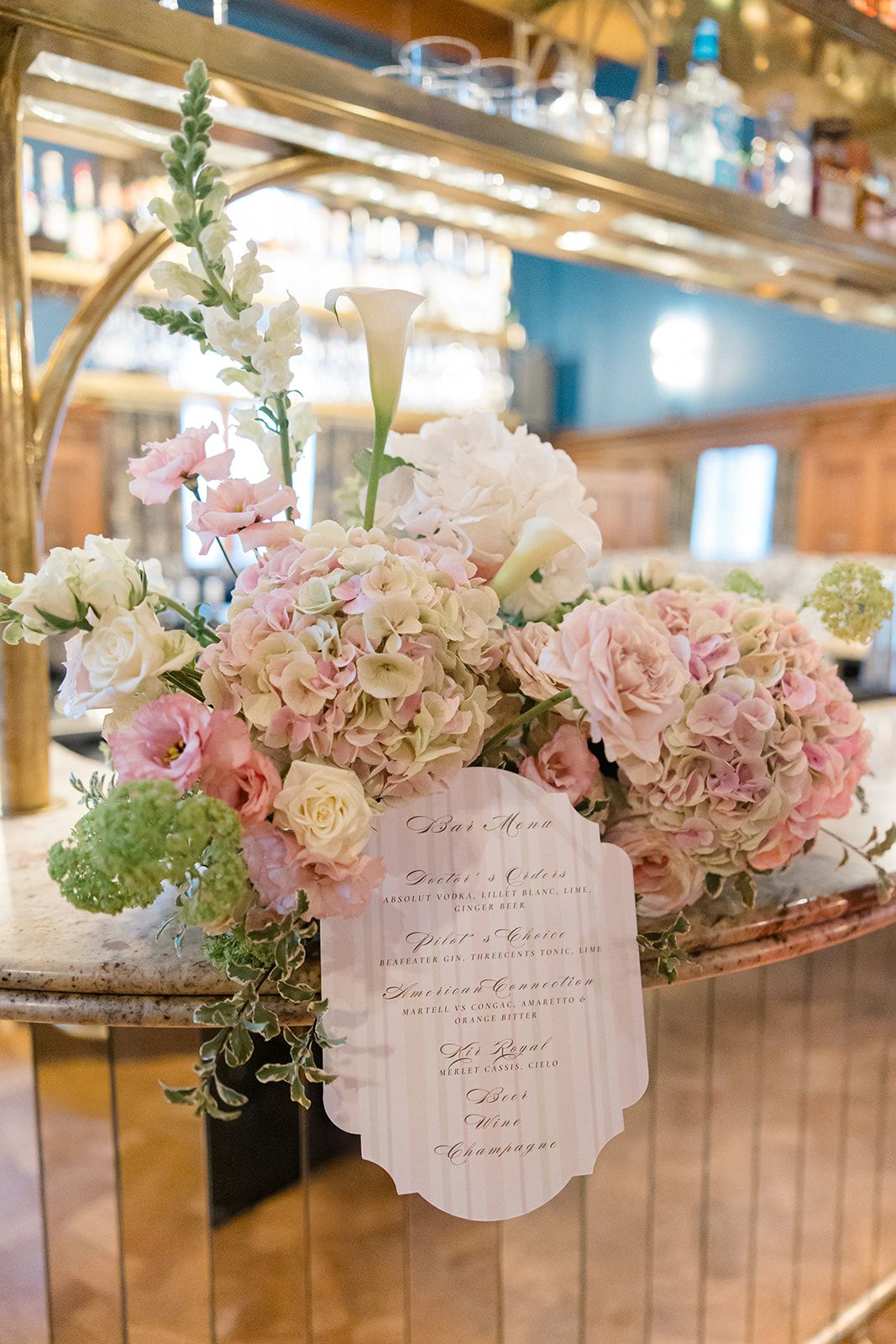 Elegant wedding reception decor featuring pink and white hydrangeas with handwritten menu cards on wooden tables.