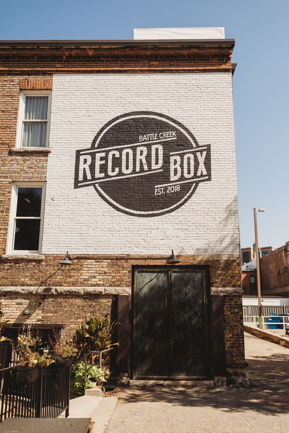 Exterior view of Record Box building with vintage-style signage on white brick walls.