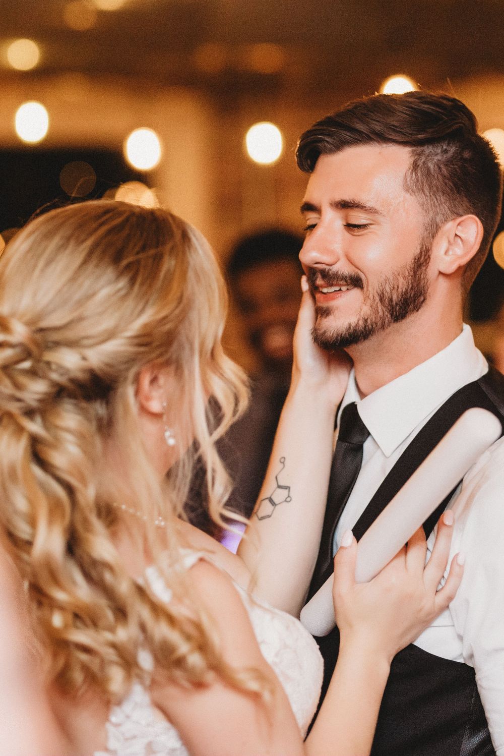 An emotional first dance moment between newlyweds under warm reception lighting.