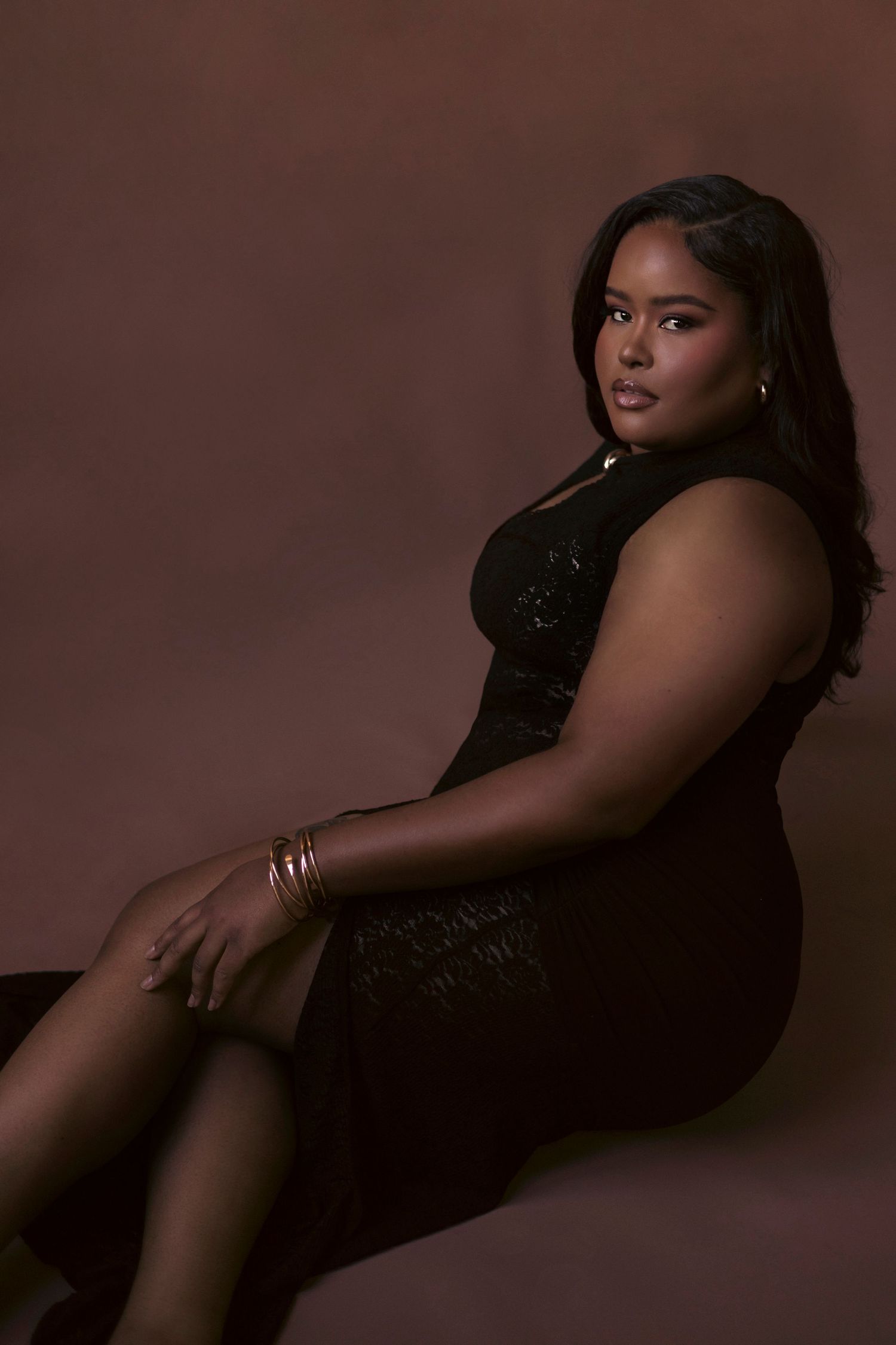 A series of moody boudoir photos showing a woman in black lingerie posing against a dark brown backdrop.