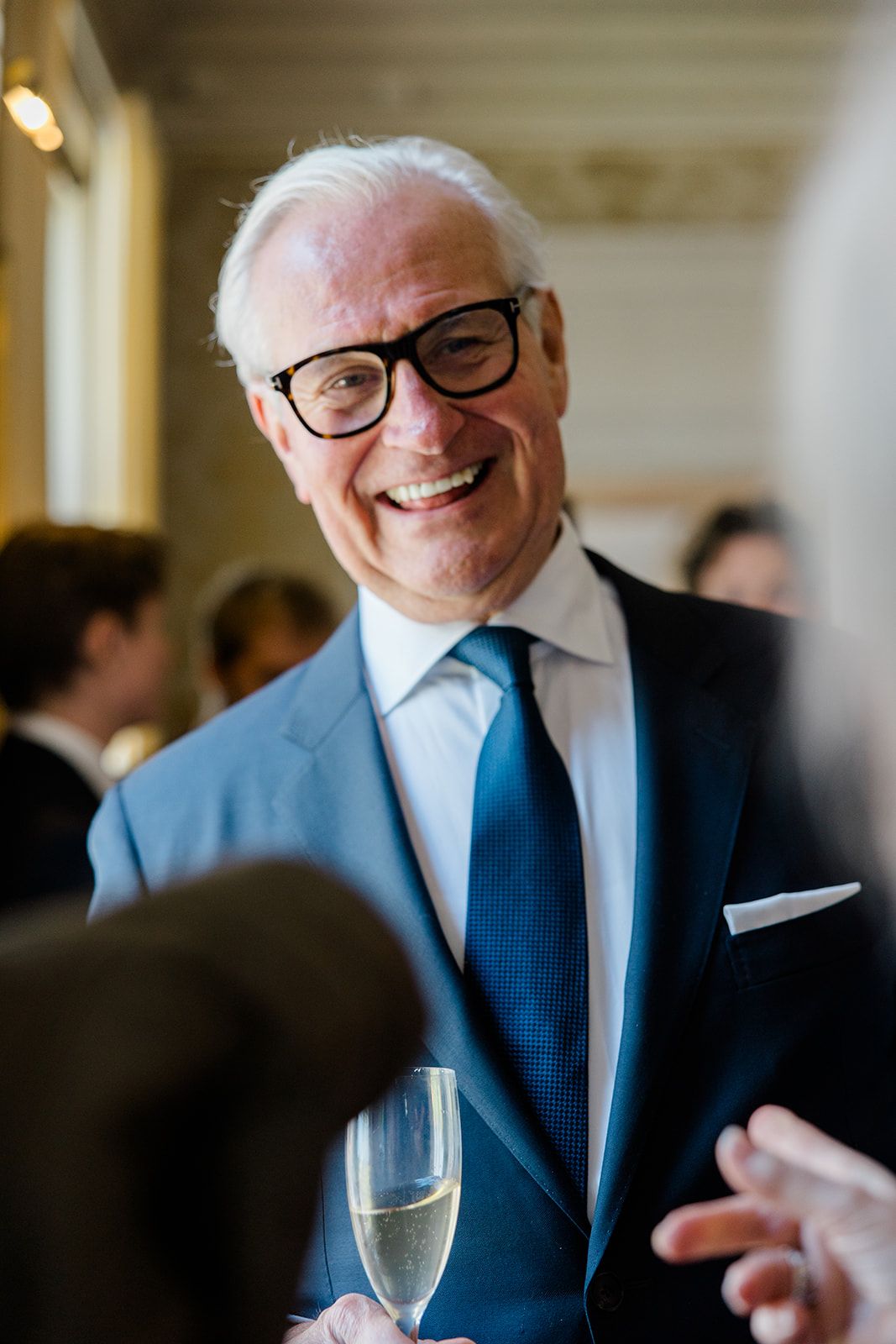 A sequence of candid moments showing a person in a blue suit and glasses at what appears to be a formal event.