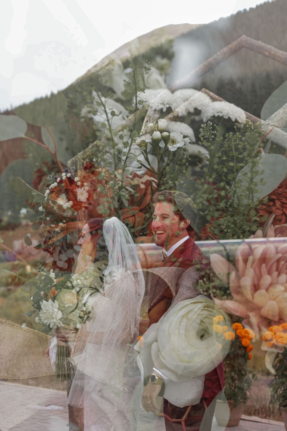 Multiple exposure wedding photograph showing joyful couple embracing outdoors with mountains and greenery in background.