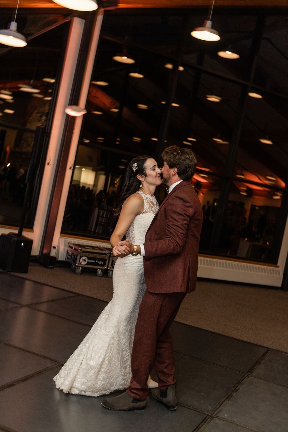 A bride and groom share an intimate dance together under dim lighting at their wedding reception venue.