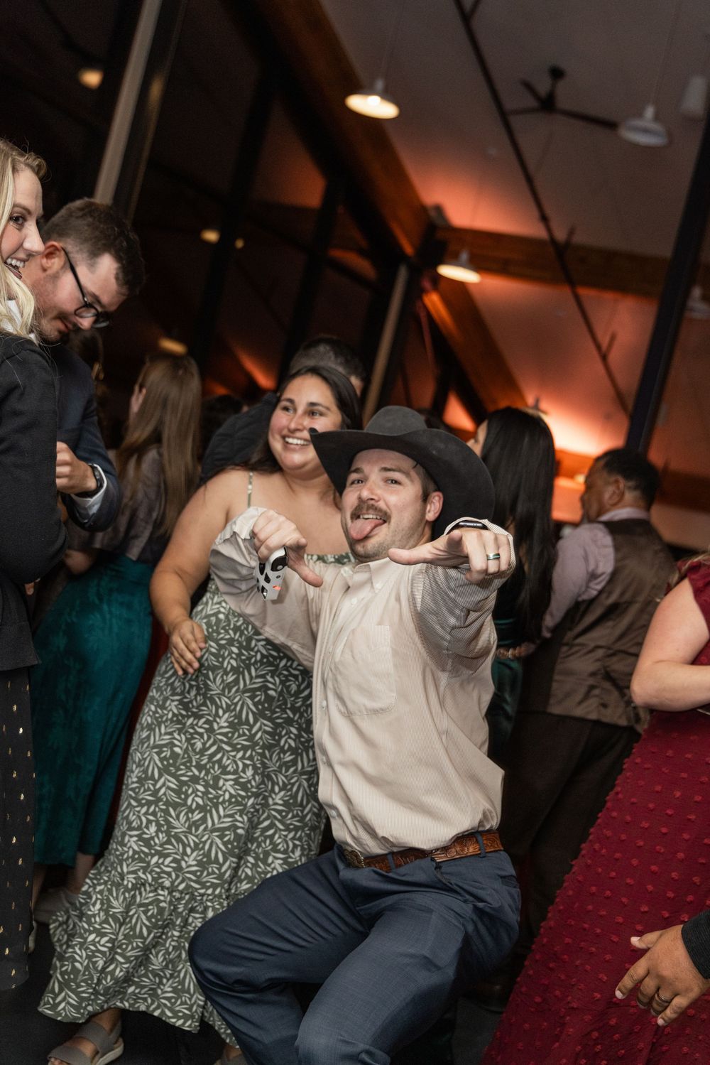 A couple dances energetically at a dimly lit venue with others visible in the background.