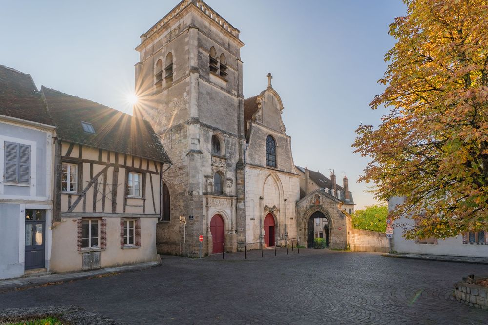 Soleil se levant derrière une Eglise sur une place de village