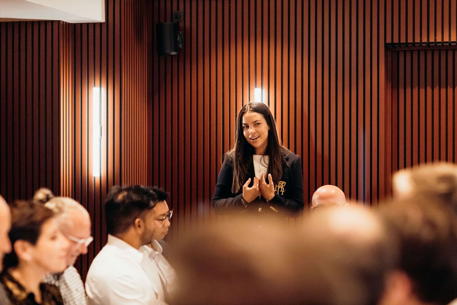 Professional business meeting in modern office with wood paneled walls and warm lighting.
