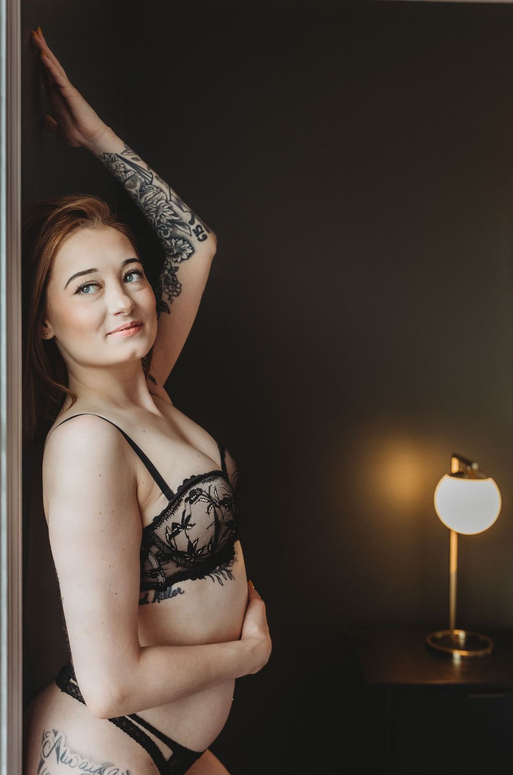 Artistic boudoir photo series in moody lighting with black lace lingerie against dark background.