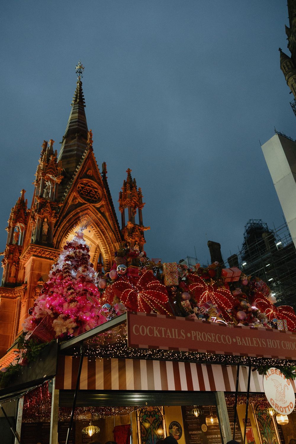 Gothic church exterior illuminated at dusk with pink floral decorations and ornate architectural details.