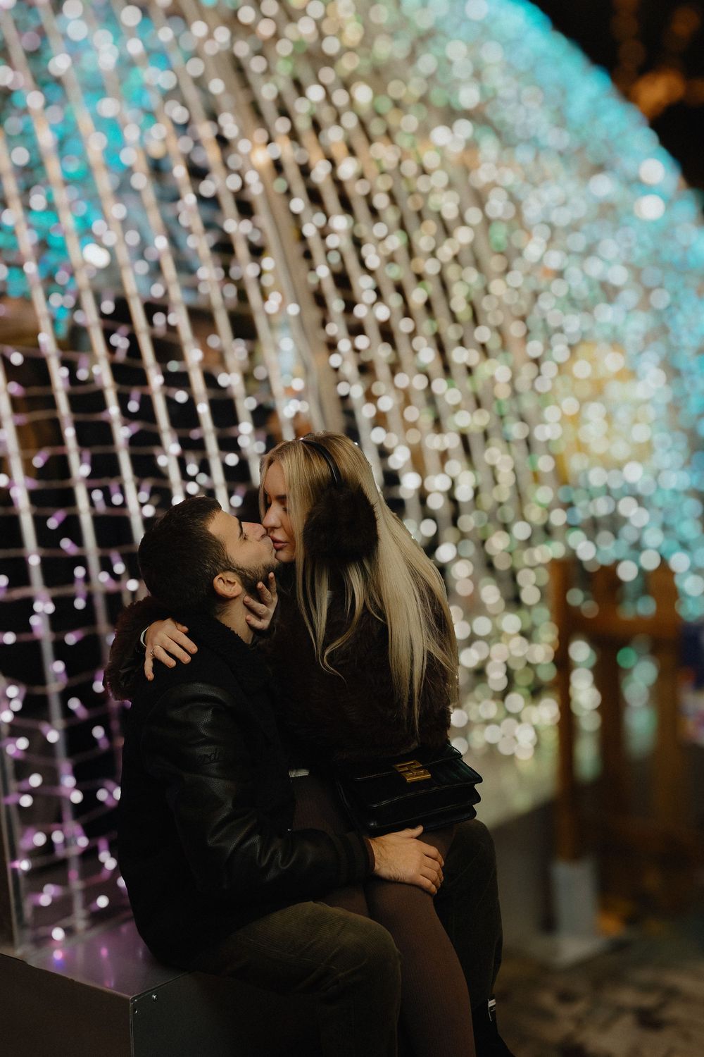 A romantic moment captured under twinkling fairy lights creating a magical bokeh effect.