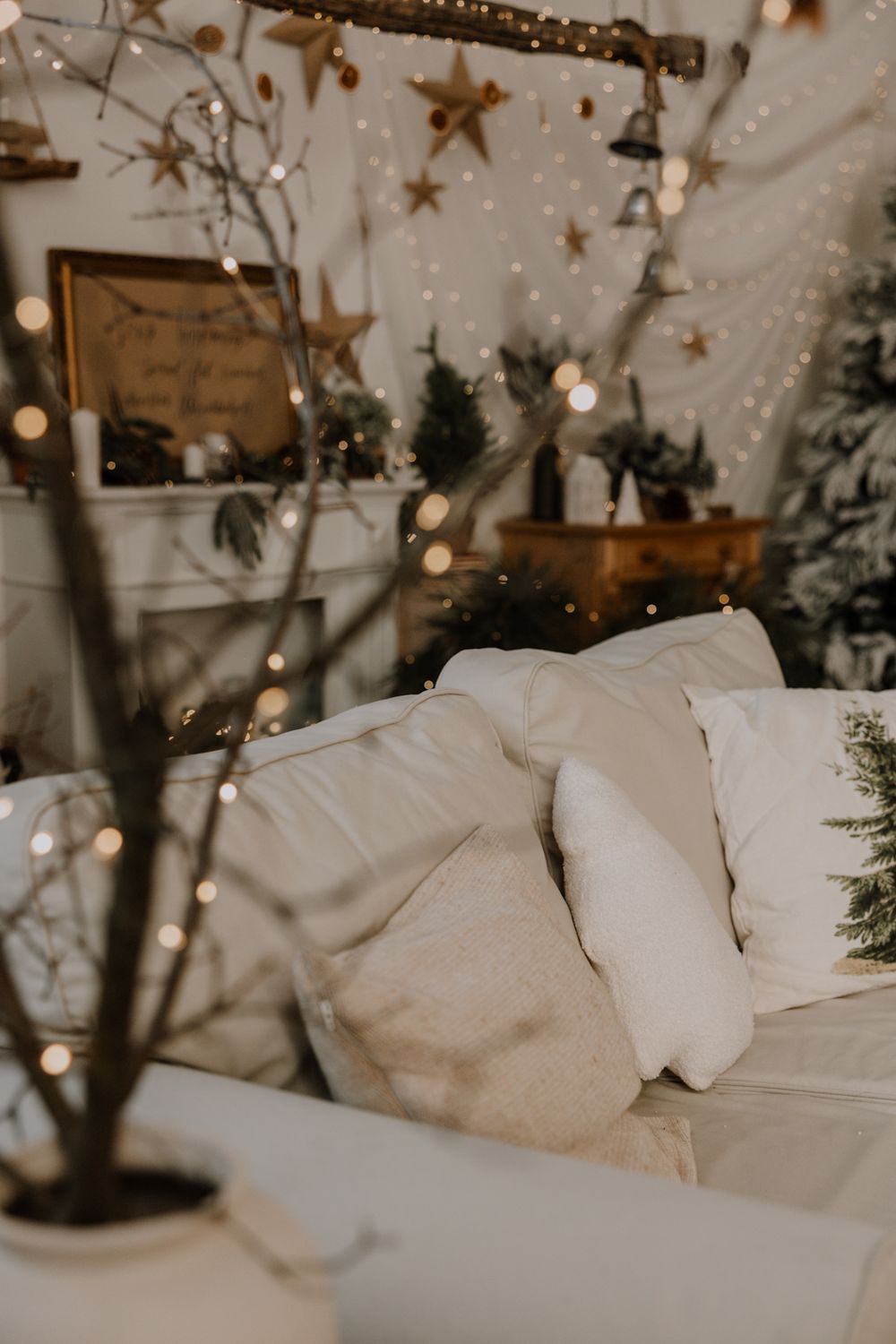 Cozy winter wedding decor with hanging gold stars, twinkling lights, and white cushions creating a magical atmosphere.