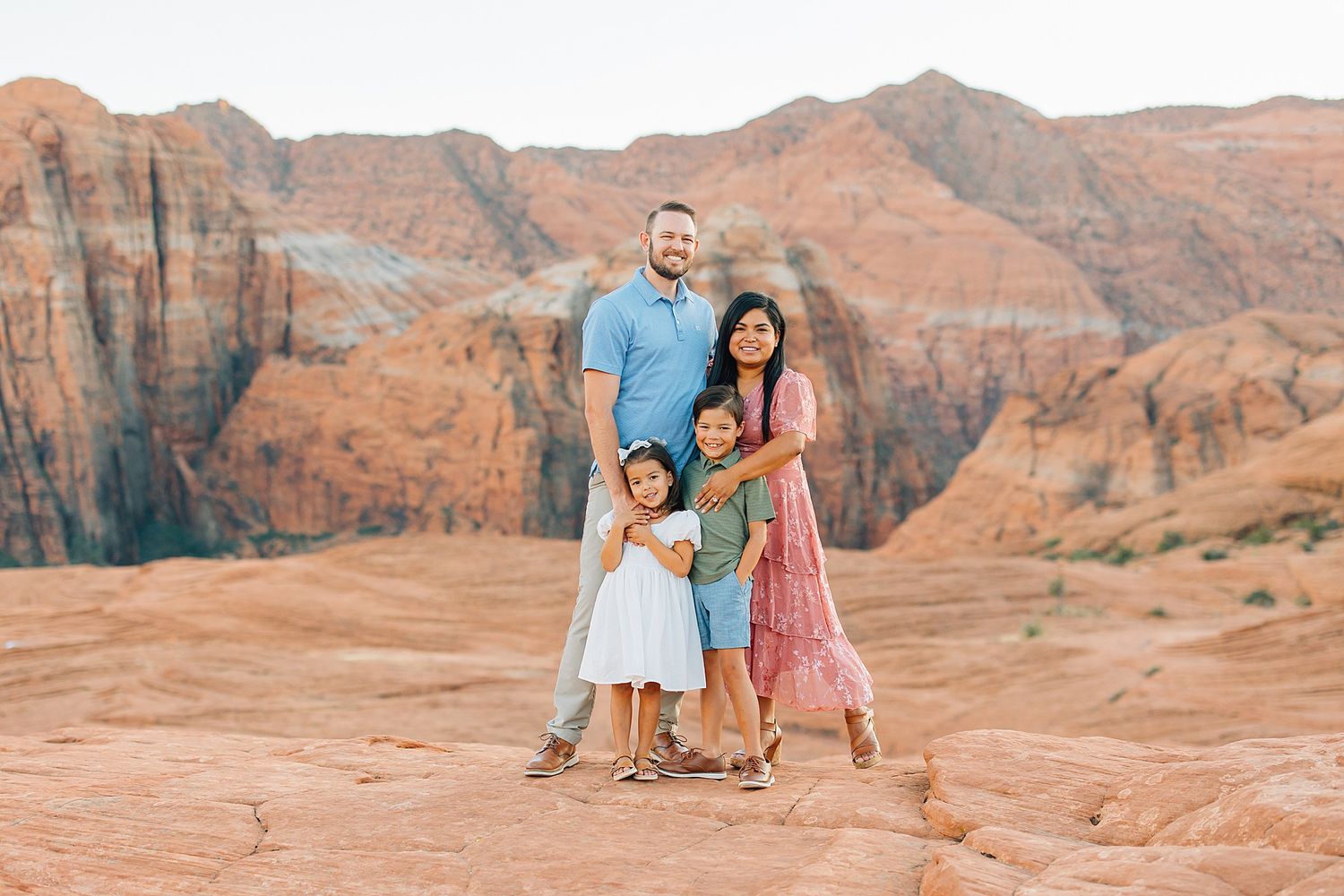 Intimate family photography session among dramatic red rock formations at sunset.