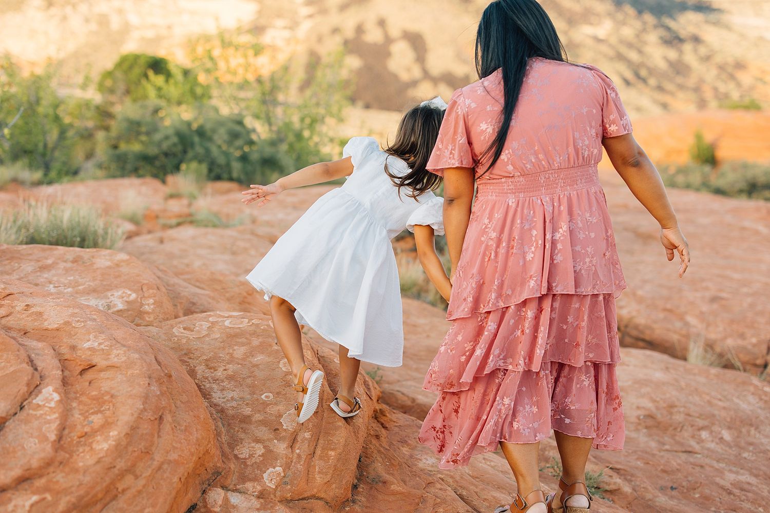 Playful interactions on red sandstone formations during golden hour photo shoot.