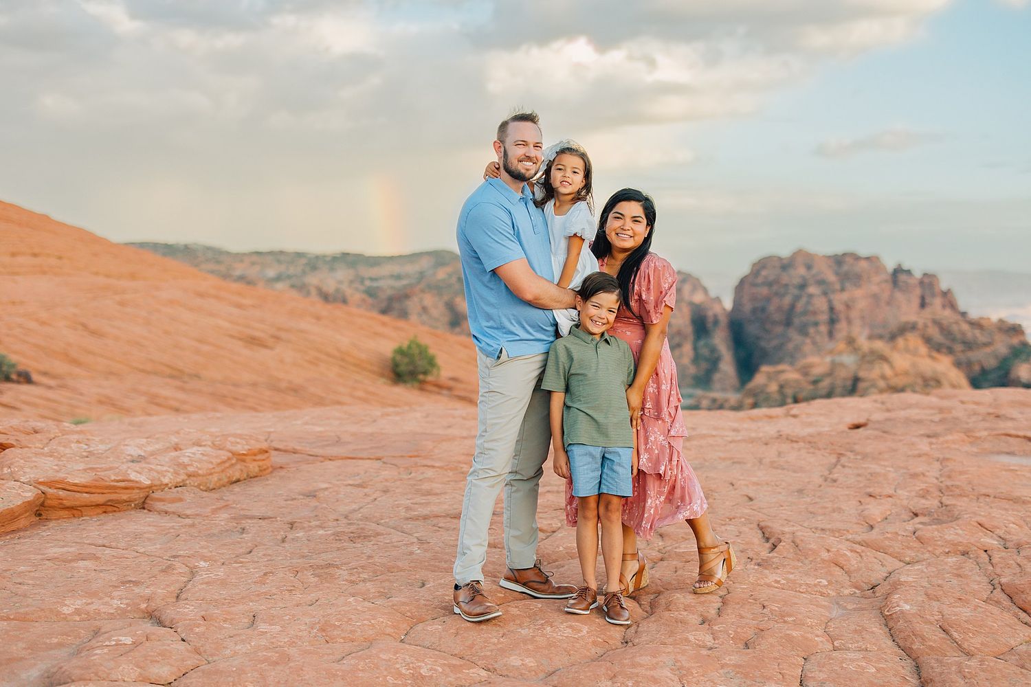 Family spending quality time together on scenic red rock formations in desert landscape.