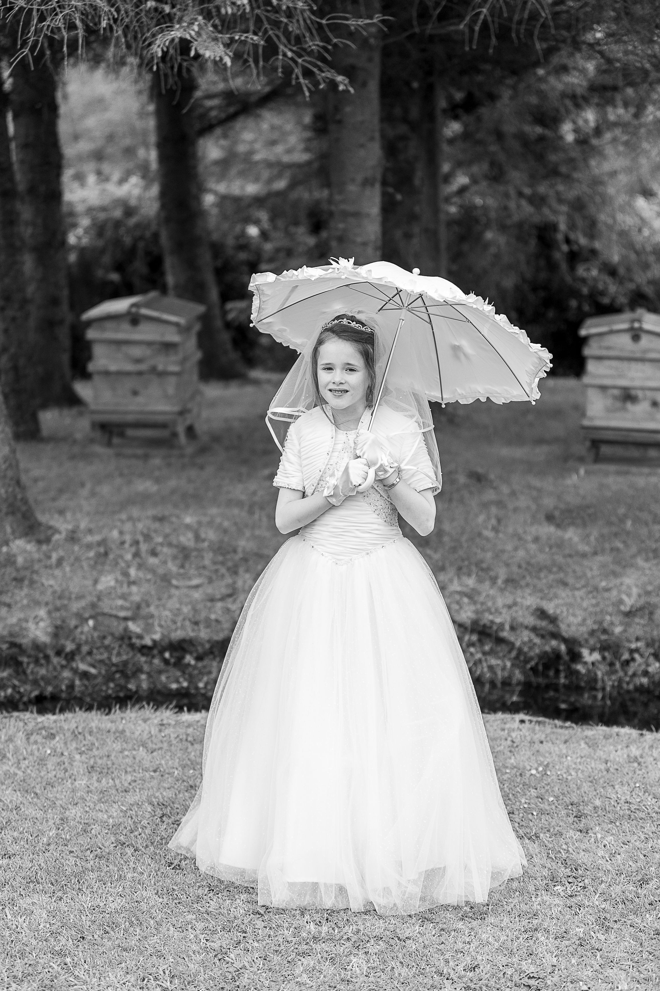 A black and white photo series showing a person in a white dress with a parasol posing in different positions on grass.  Newtownbutler