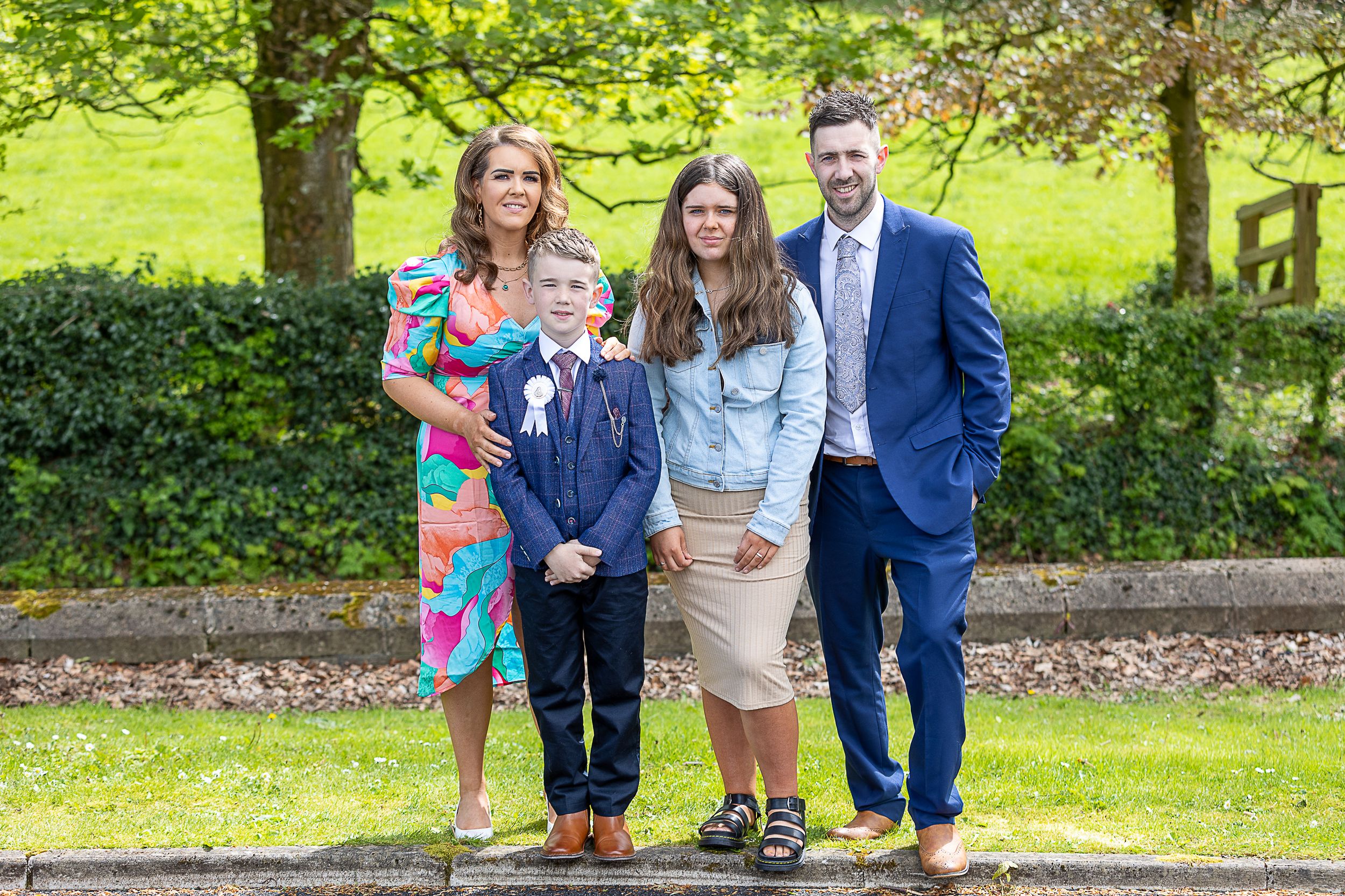 Family members walk together and share joyful moments in a lush green park setting on a sunny day.  Lisnaskea Communions