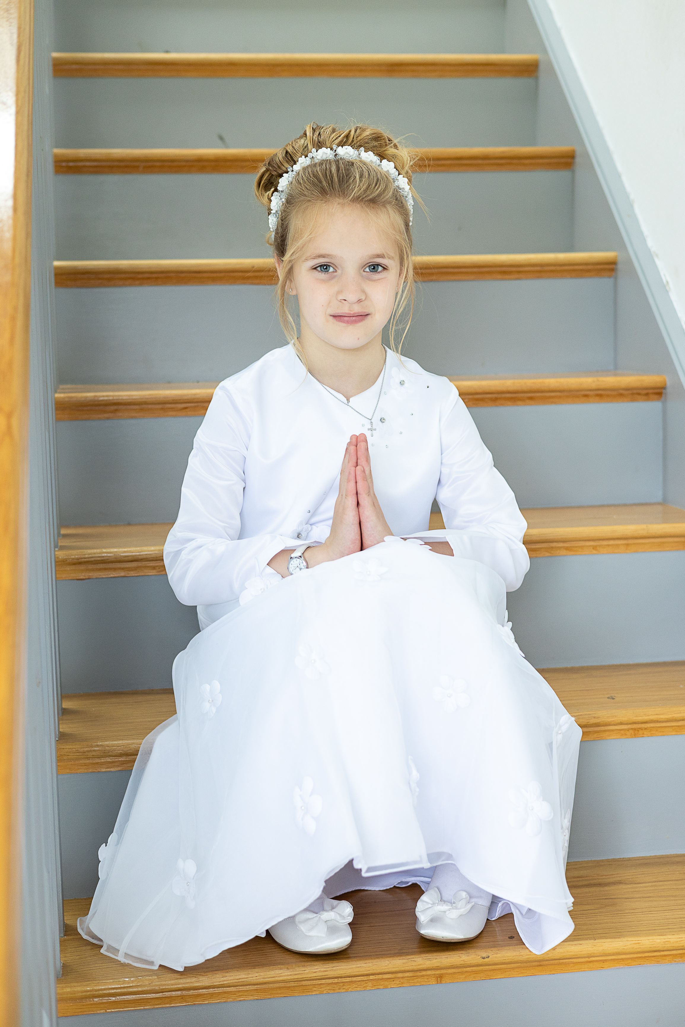 young child in white dresses sit on wooden stairs at Swadlinbar Communions