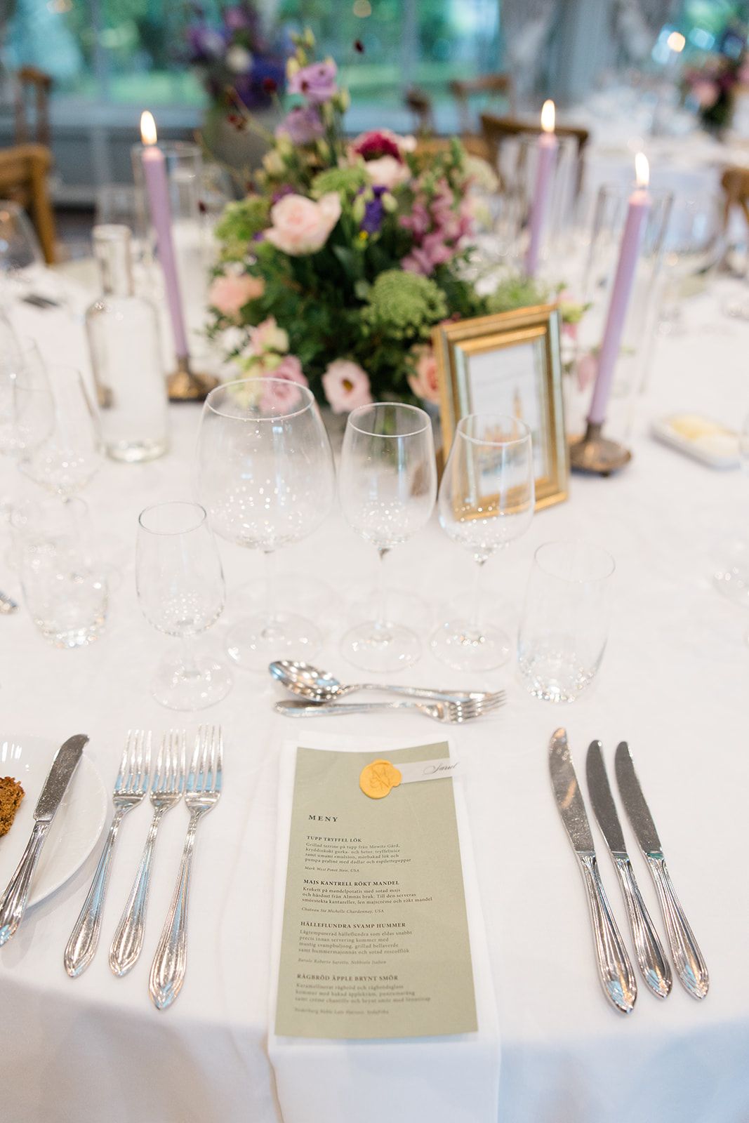 Elegant wedding reception table settings with white linens, floral centerpieces, and menus displayed at each place setting.