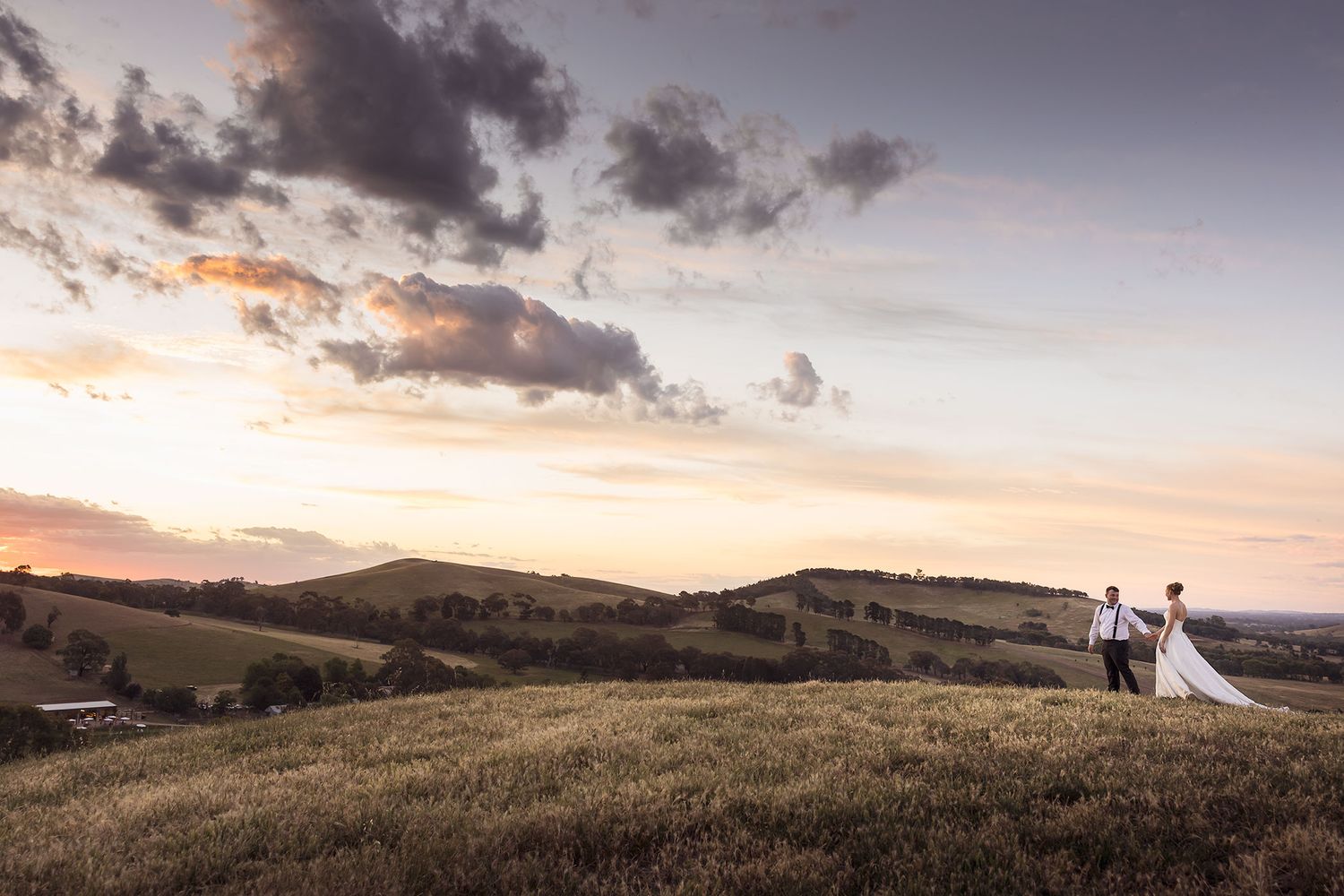 Panoramic view of rolling hills and dramatic clouds during sunset at a mountain wedding venue.