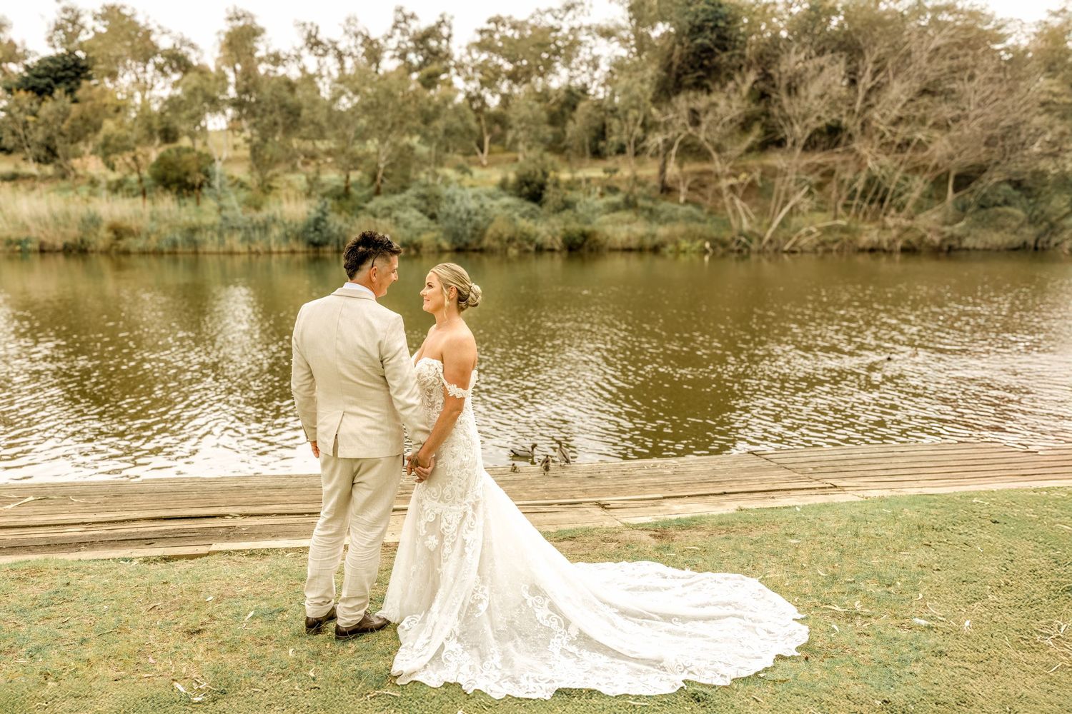 Romantic wedding photography session by a tranquil lakeside in warm sunset light.