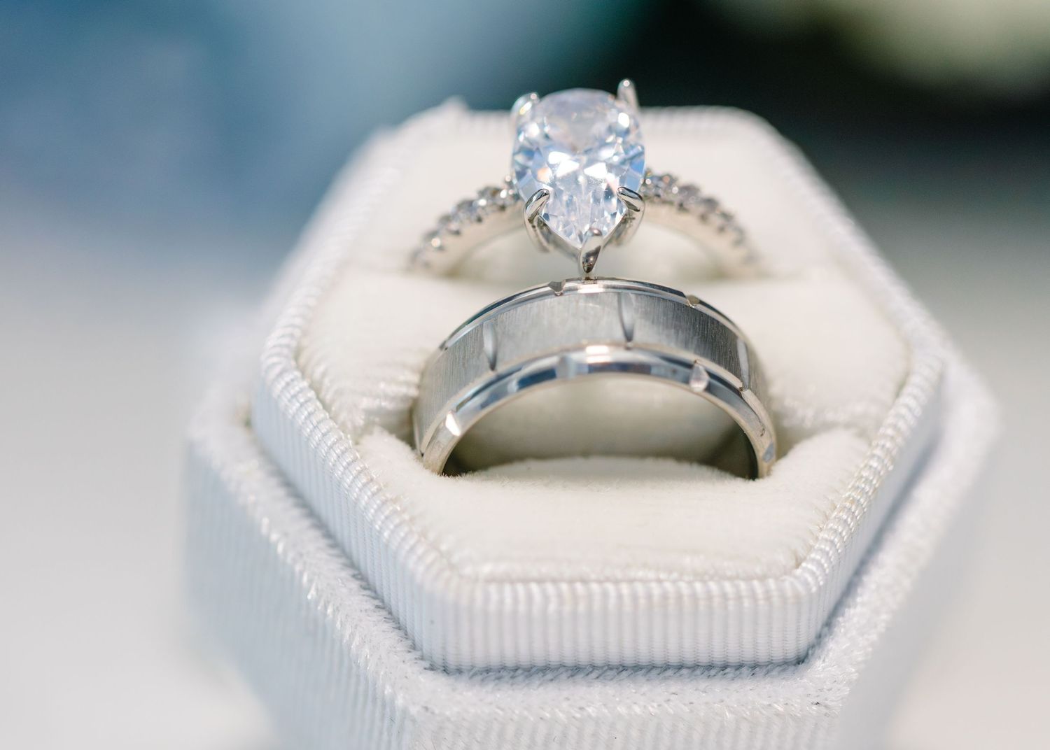 Wedding rings displayed in a white hexagonal ring box with diamond engagement ring.