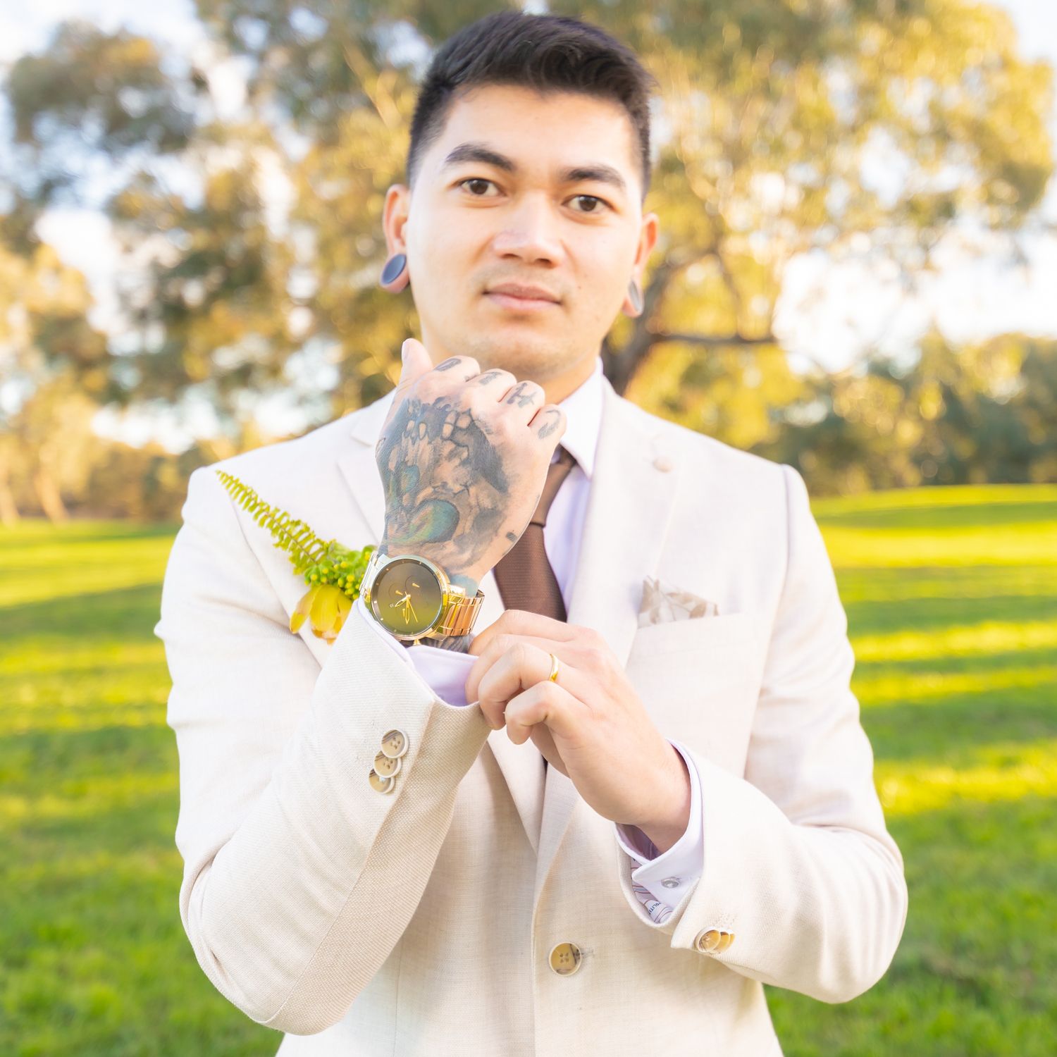 Person in cream-colored suit jacket holds up decorative wedding signage outdoors.