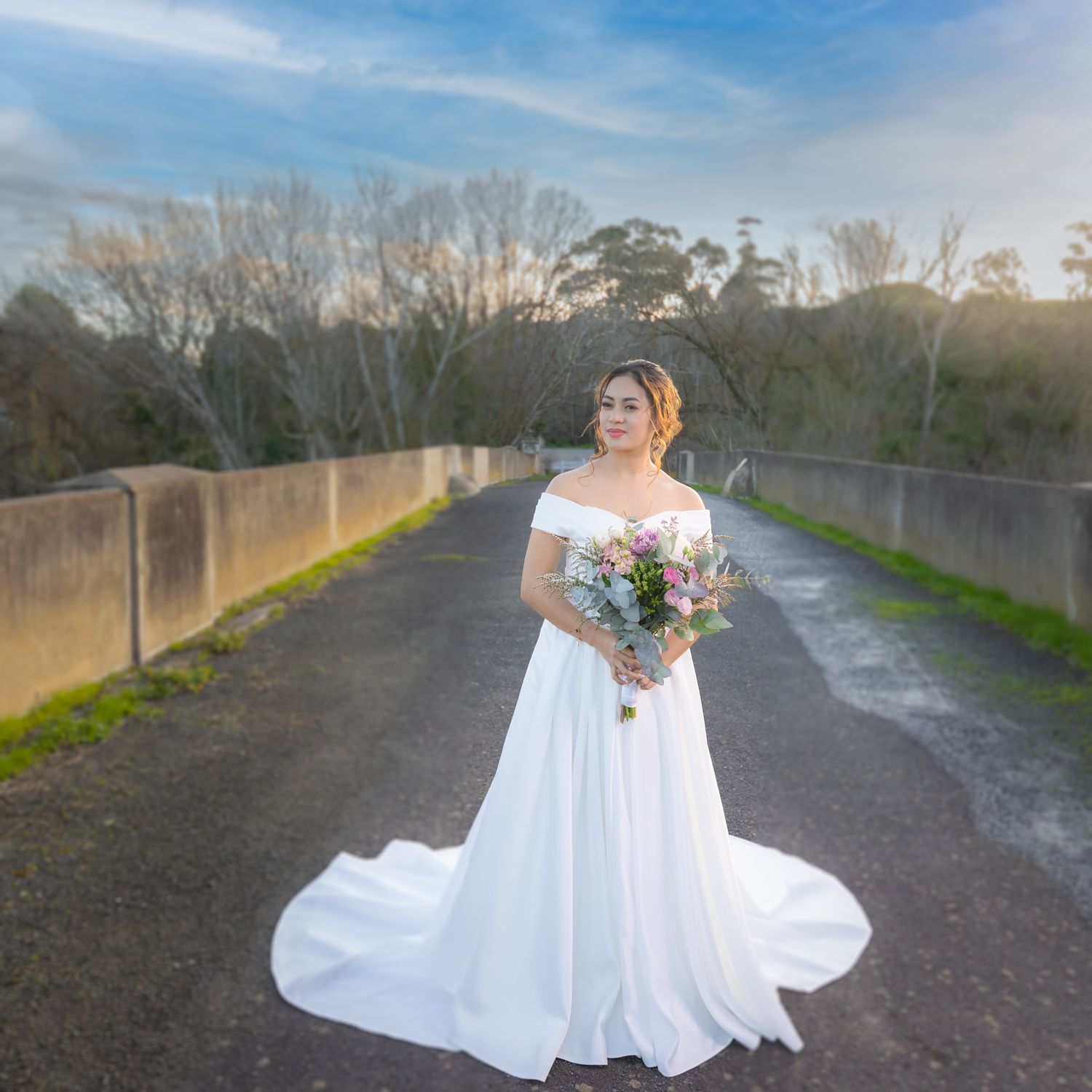 A flowing white wedding dress twirls gracefully on a path during sunset.