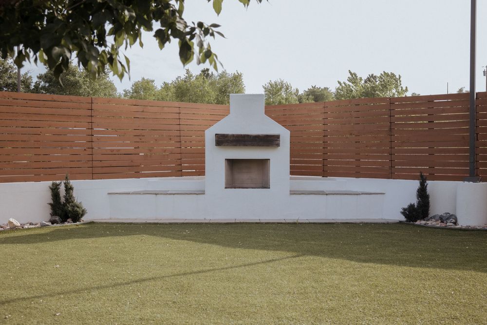 Modern outdoor patio area with horizontal wood privacy fence panels and white stucco walls creating a serene backyard space.