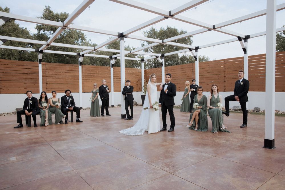 Wedding guests gather under a white tent canopy during an outdoor ceremony.
