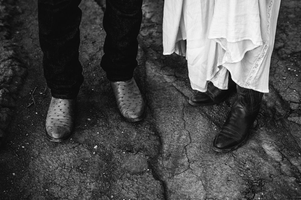 Black and white close-up of couple's feet, man in cowboy boots and woman in black boots.