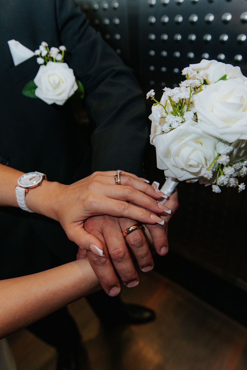 Close-up sequence of hands with wedding rings and white roses.