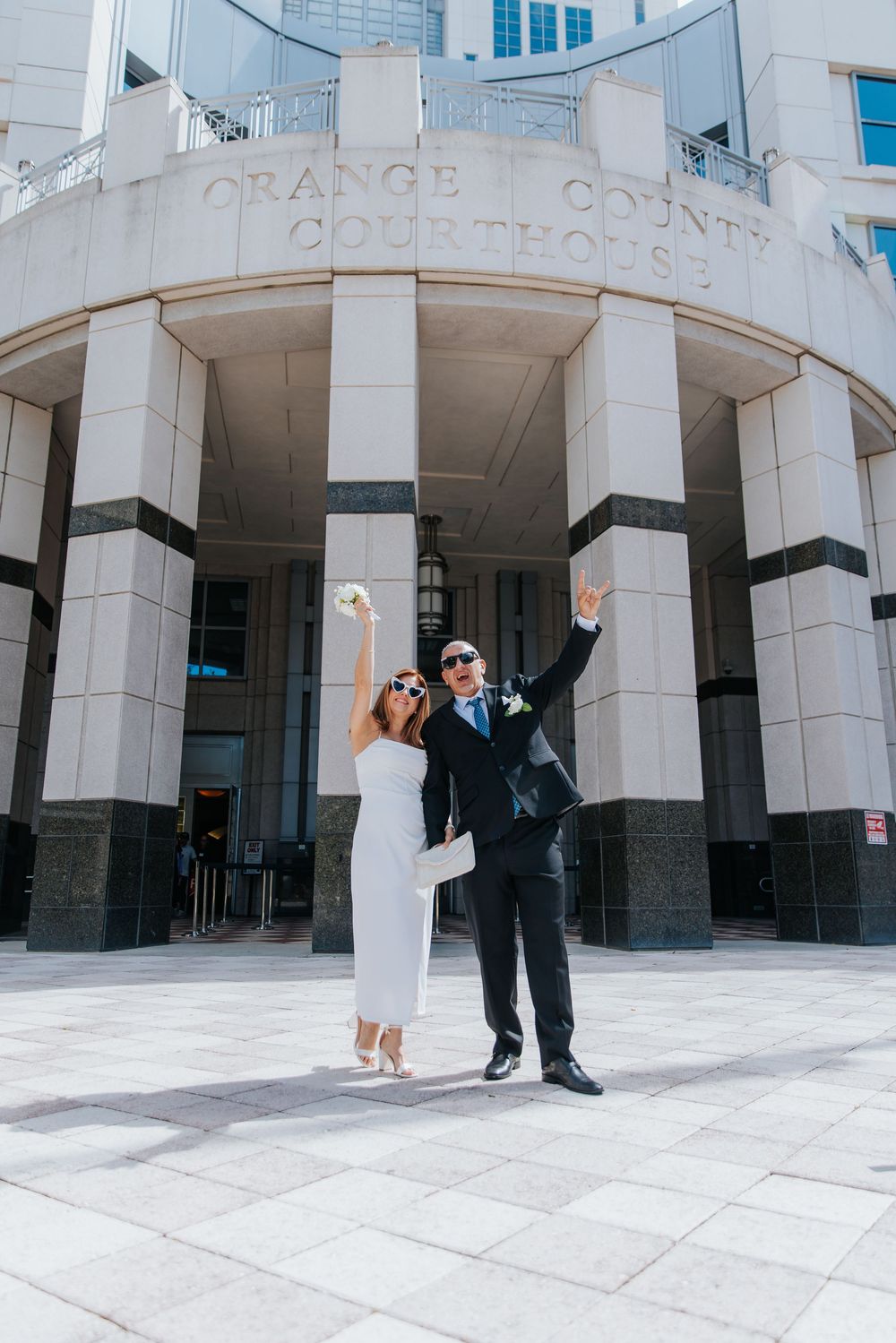 Wedding couple poses in front of modern white architectural columns.