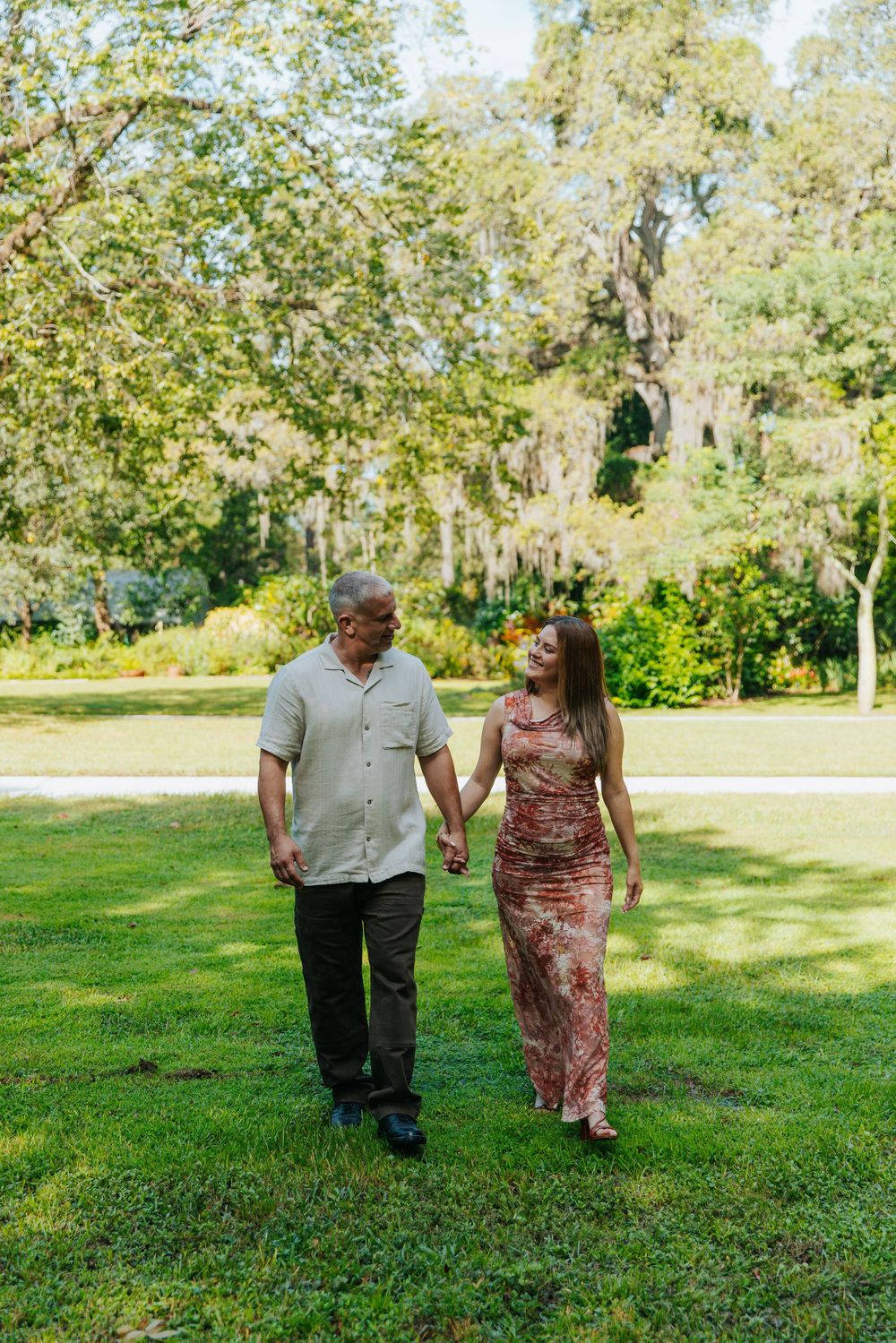 A couple takes a romantic stroll through a lush garden pathway.