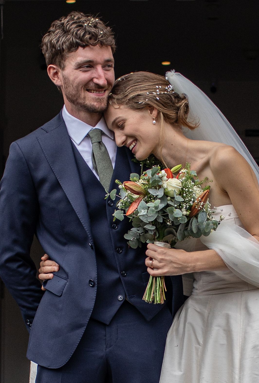 A series of intimate wedding photos showing a couple in navy suit and white dress sharing tender moments with a floral bouquet.