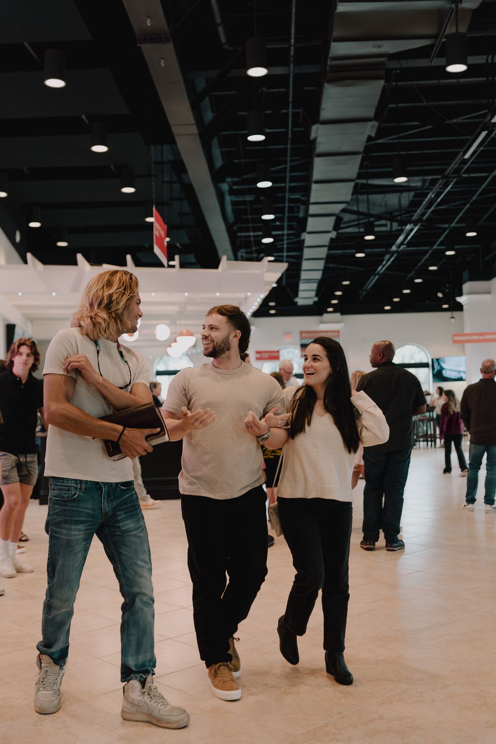 Dancers practicing line dancing moves in a large indoor studio space with polished floors and overhead lighting.