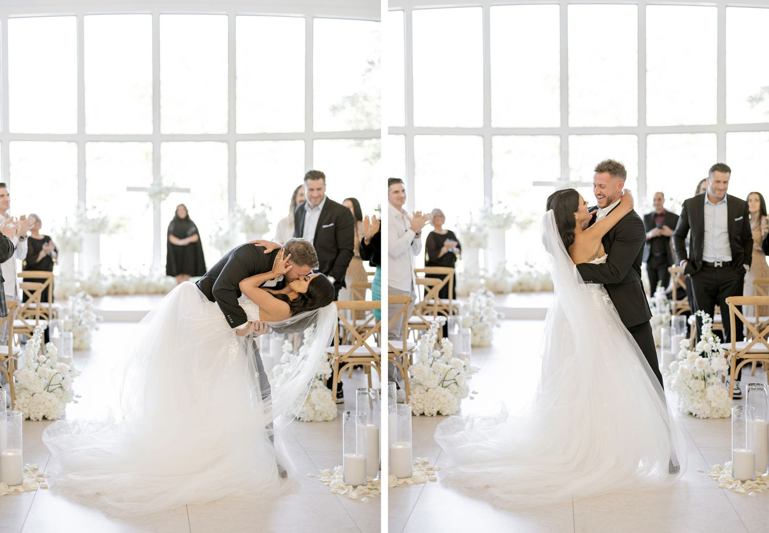 A wedding party poses in an elegant white reception venue with floor-to-ceiling windows and floral centerpieces.