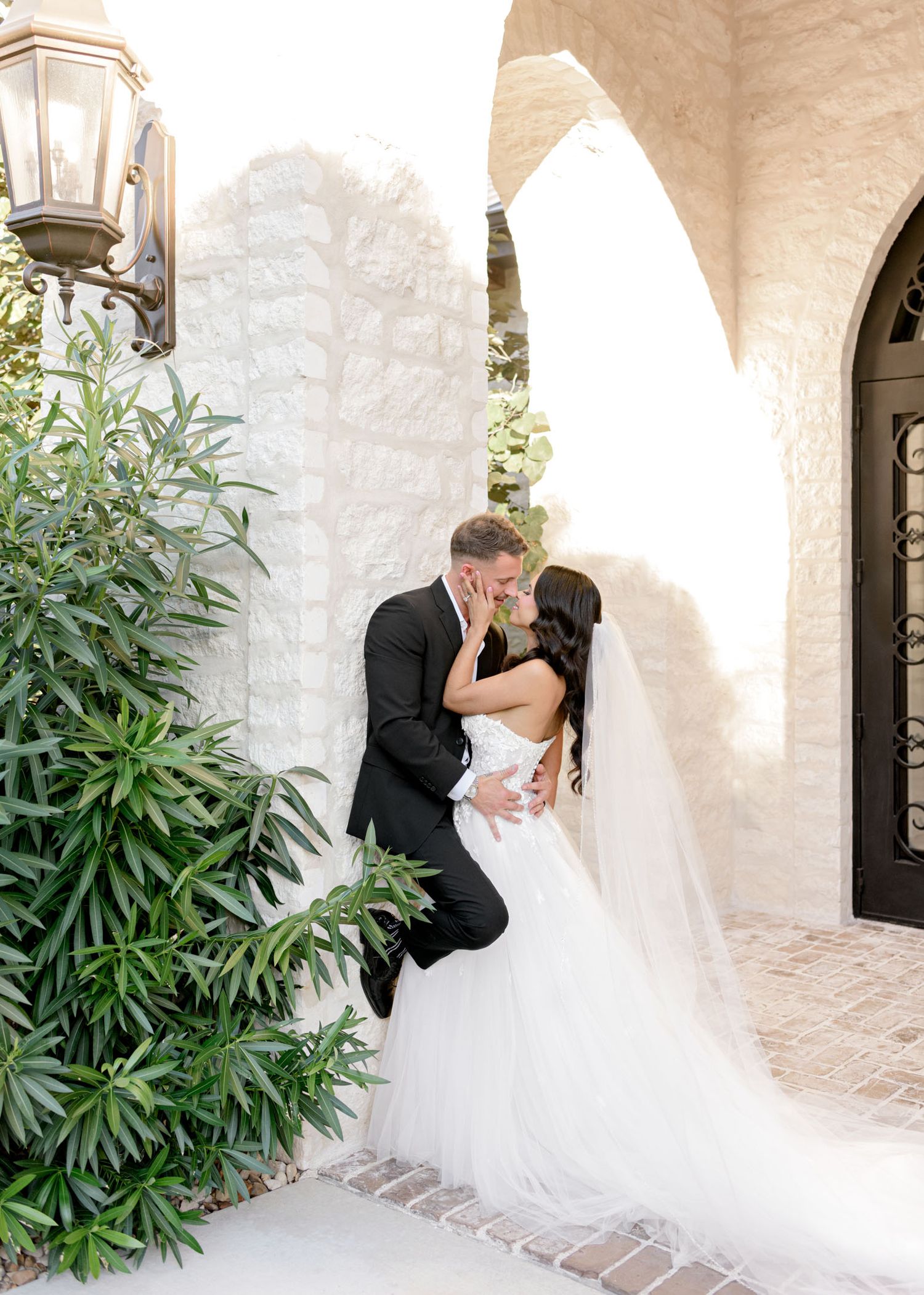 A romantic wedding photo sequence shows a couple sharing intimate moments against a white stucco wall with lush greenery.